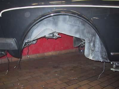 Ein schwarzes Auto steht auf einem Ziegelboden in einer Garage.