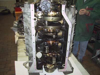 Ein Mann steht neben einer Kurbelwelle eines Automotors