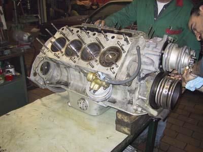 Ein Mann steht neben einem großen Motor, der auf einem Tisch steht.