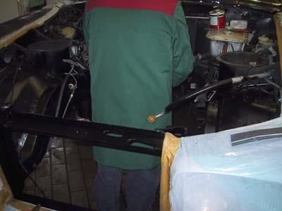 Ein Mann in einer grünen Jacke arbeitet an einem Automotor.