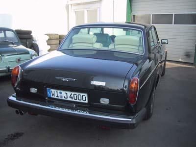 Ein schwarzes Auto mit dem Nummernschild W17J4000 steht vor einer Garage.