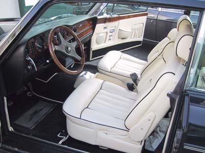 Der Innenraum eines schwarzen Autos mit weißen Sitzen und einem Holzlenkrad