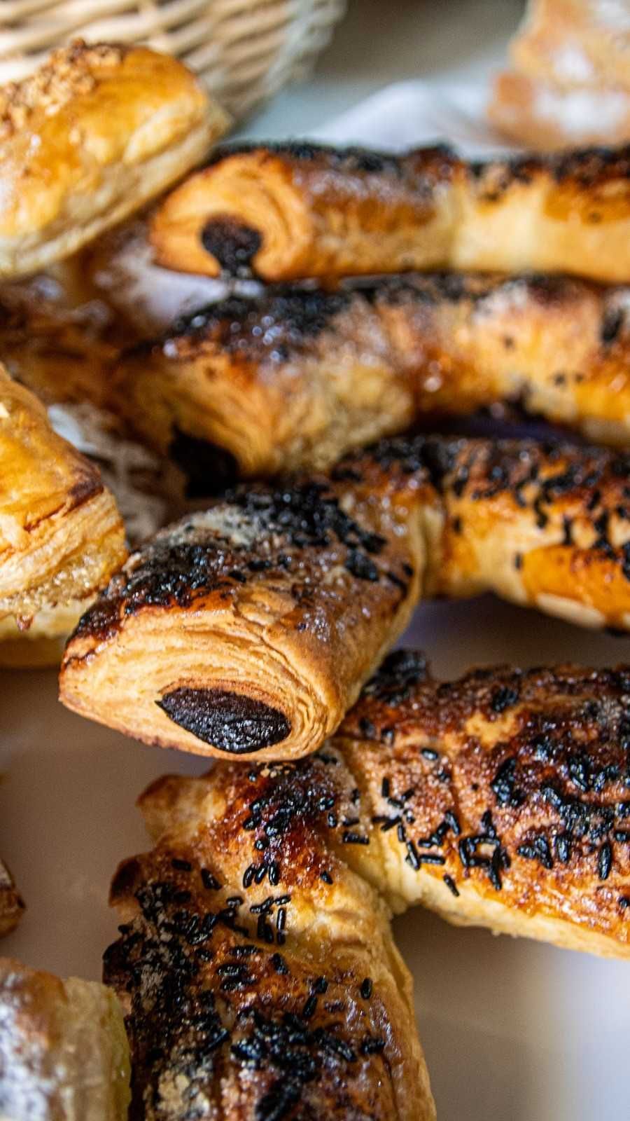 Tres panes redondos de color marrón dorado, colocados en una cesta tejida y forrada con arpillera.