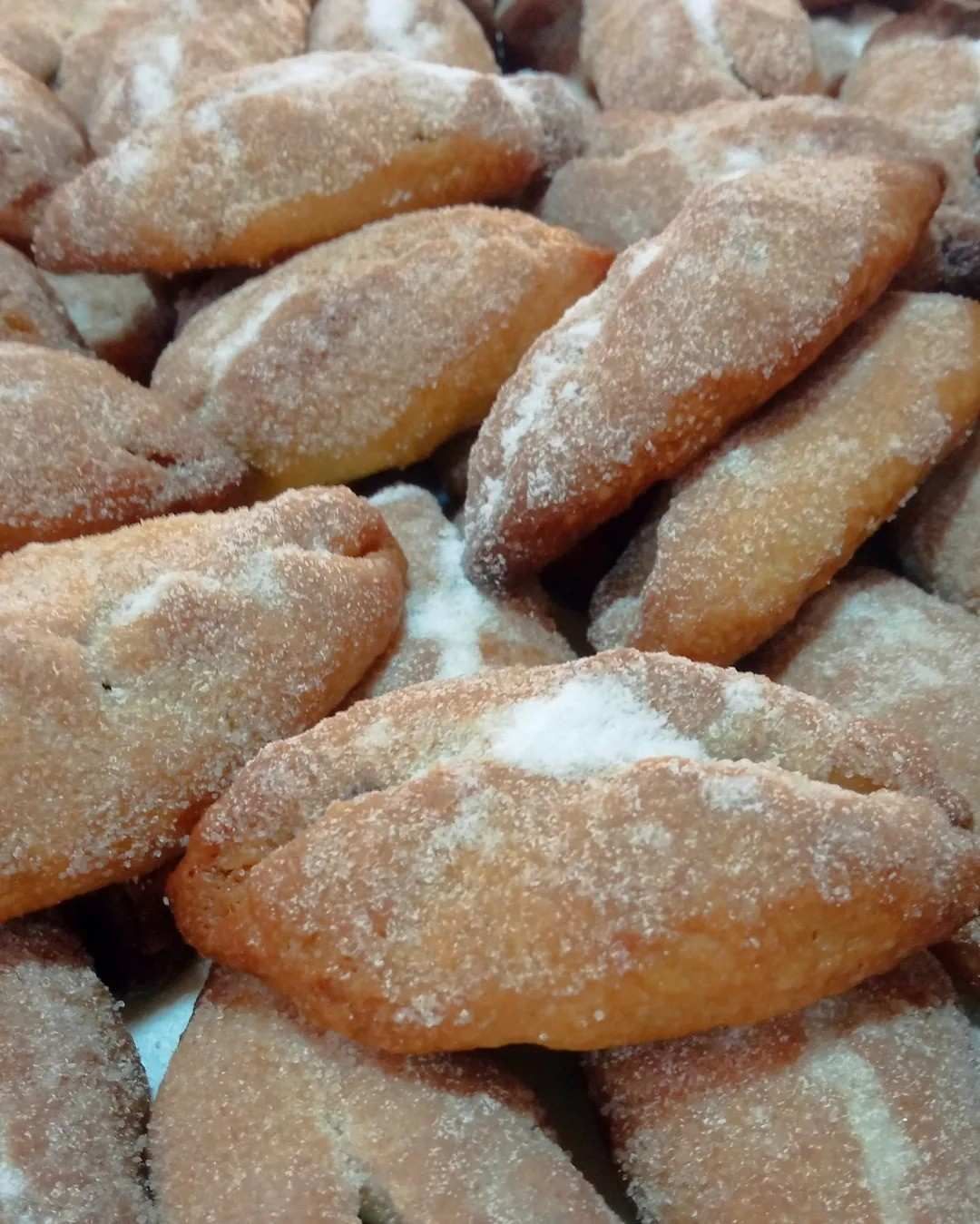 En una cesta de mimbre poco profunda reposa una hogaza grande y redonda de pan artesanal, crujiente.