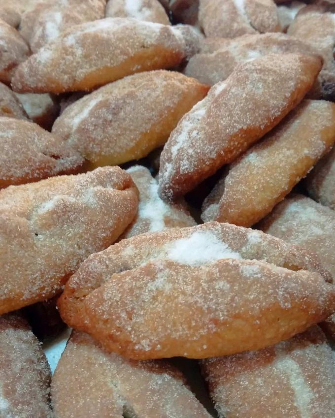 En una cesta de mimbre poco profunda reposa una hogaza grande y redonda de pan artesanal, crujiente.