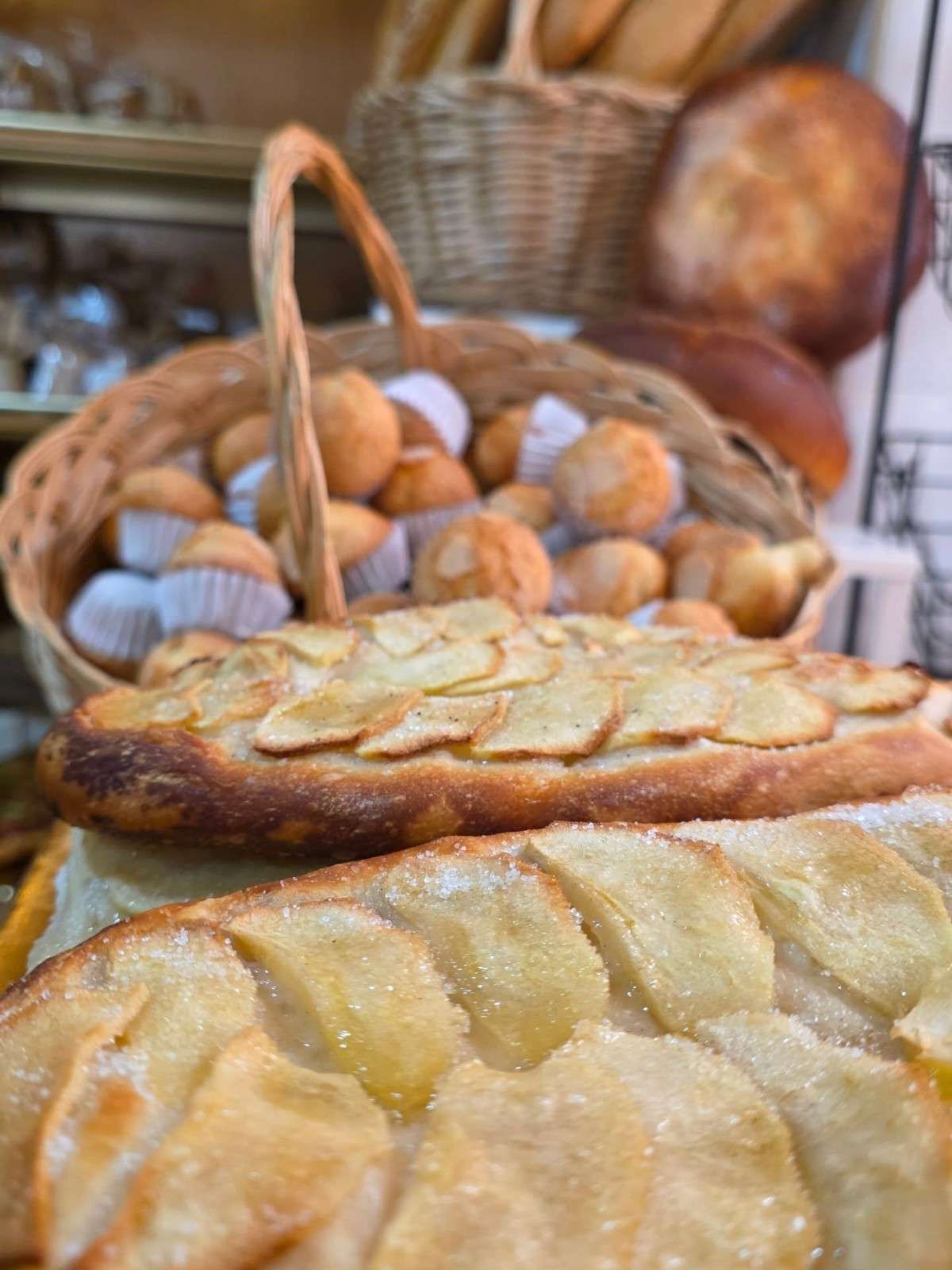 Un gran pan redondo y crujiente, con nueces troceadas, reposando en una cesta de mimbre forrada con papel pergamino.