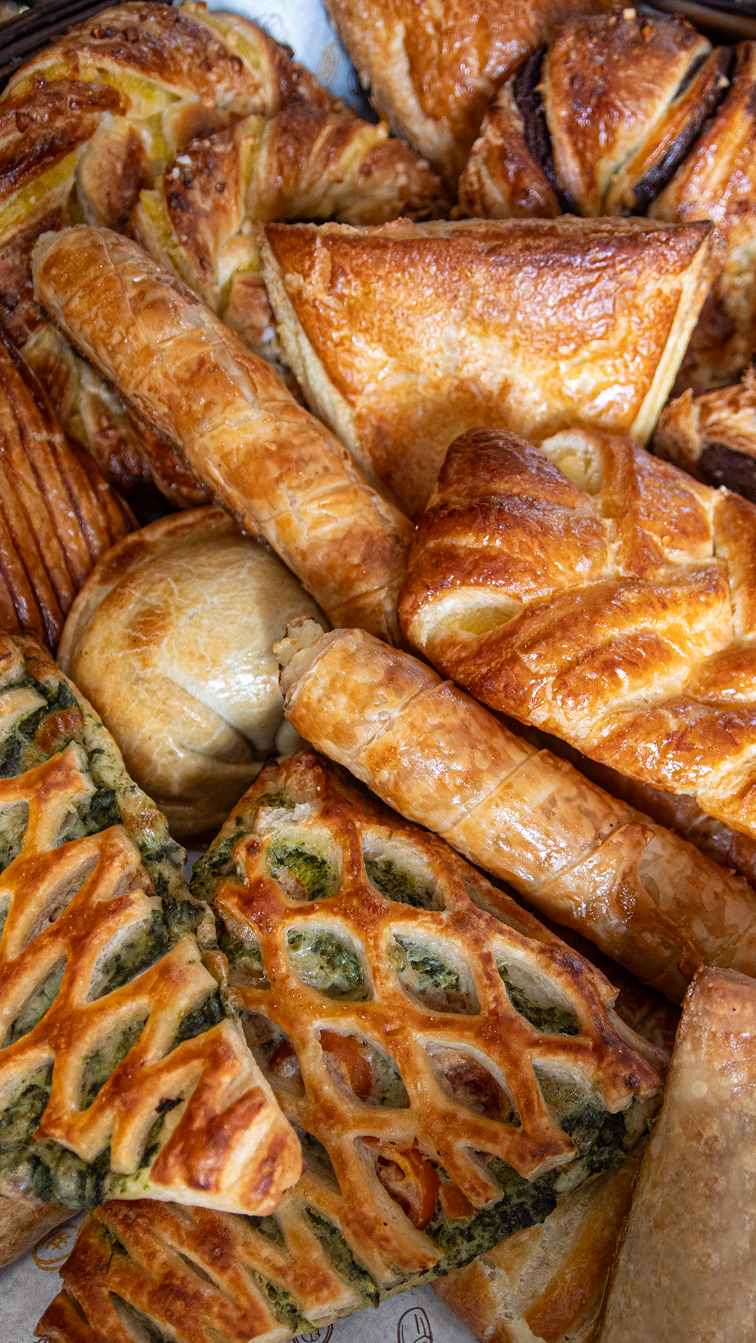 Varias hogazas redondas y rústicas de pan de masa madre con la parte superior marcada, dispuestas en una cesta de mimbre.