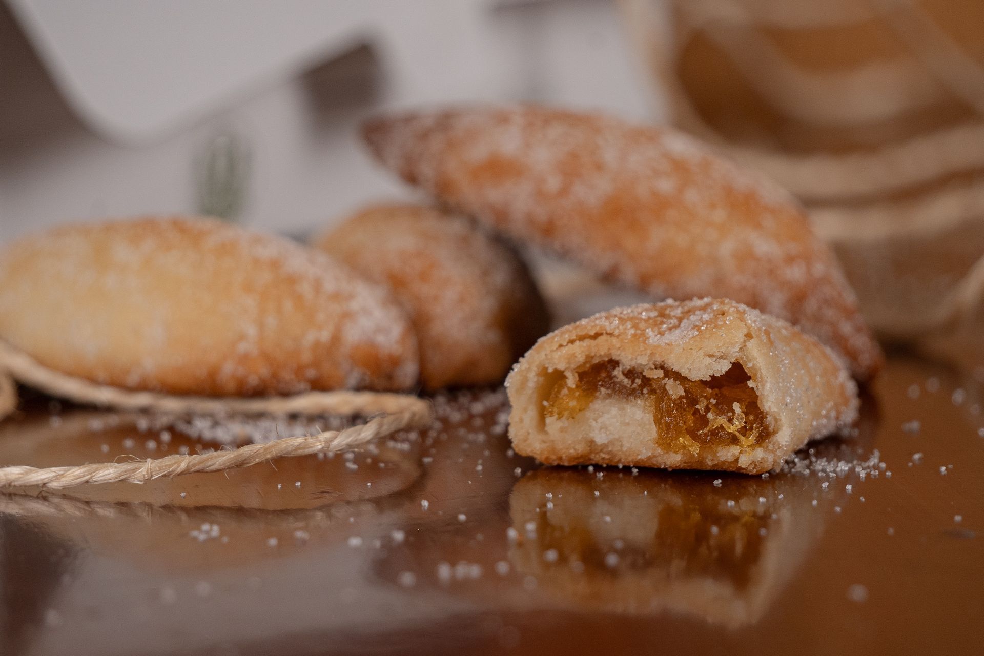 Pasteles espolvoreados con azúcar sobre una mesa de madera, uno de ellos abierto dejando ver el relleno.