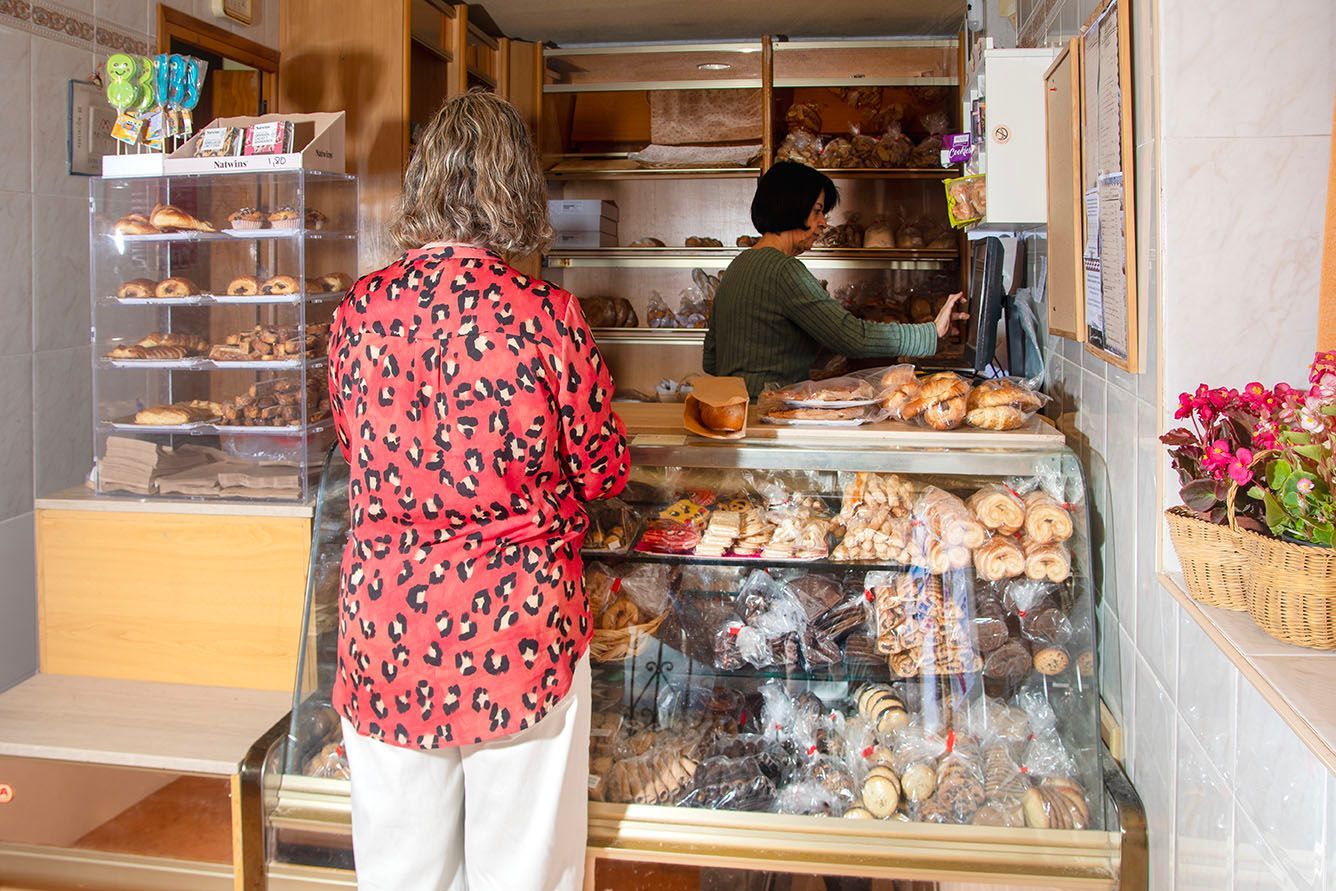 Un gran pan redondo y crujiente, con nueces troceadas, reposando en una cesta de mimbre forrada con papel pergamino.