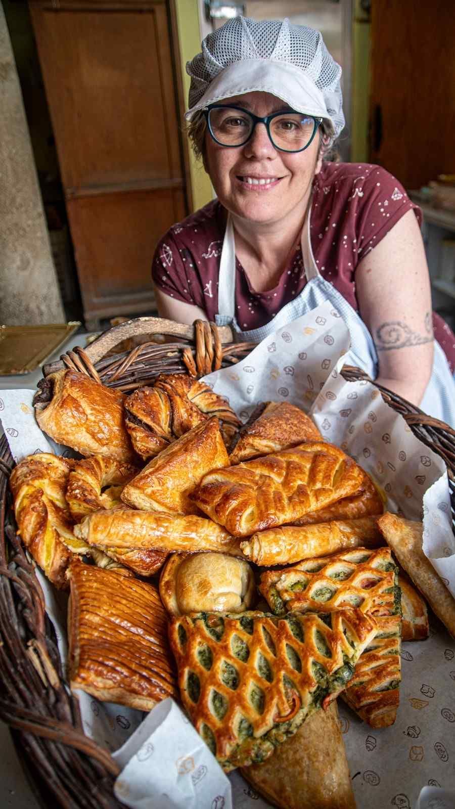 Varias hogazas redondas y rústicas de pan de masa madre con la parte superior marcada, dispuestas en una cesta de mimbre.