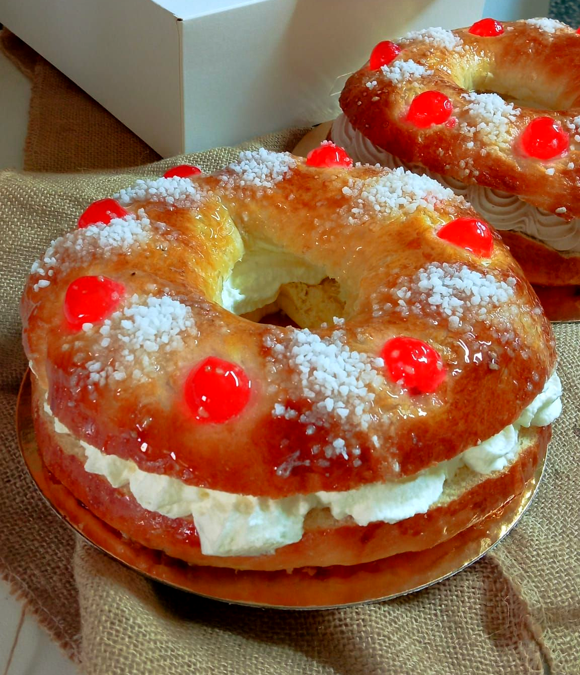 En primer plano, dos panes planos con fruta, junto a una cesta de magdalenas y panes más grandes.