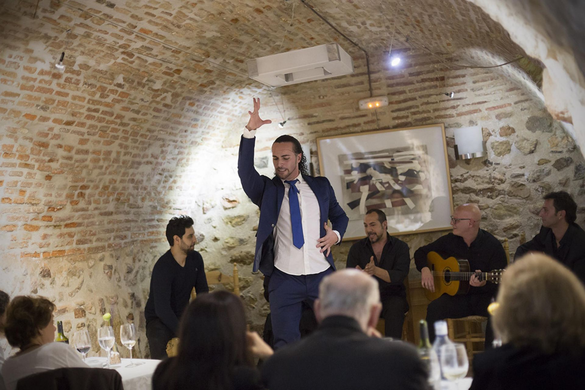 Un hombre con traje y corbata está bailando delante de un grupo de personas.
