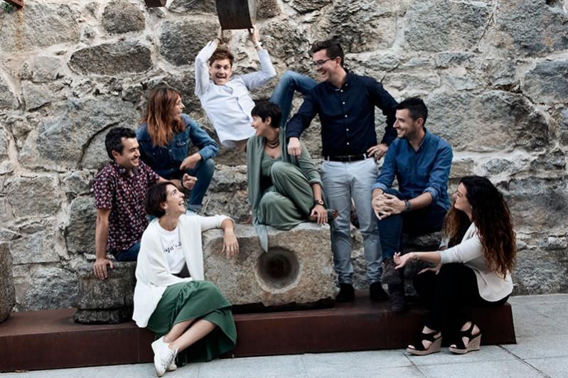 Un grupo de personas está sentado en una roca frente a un muro de piedra.