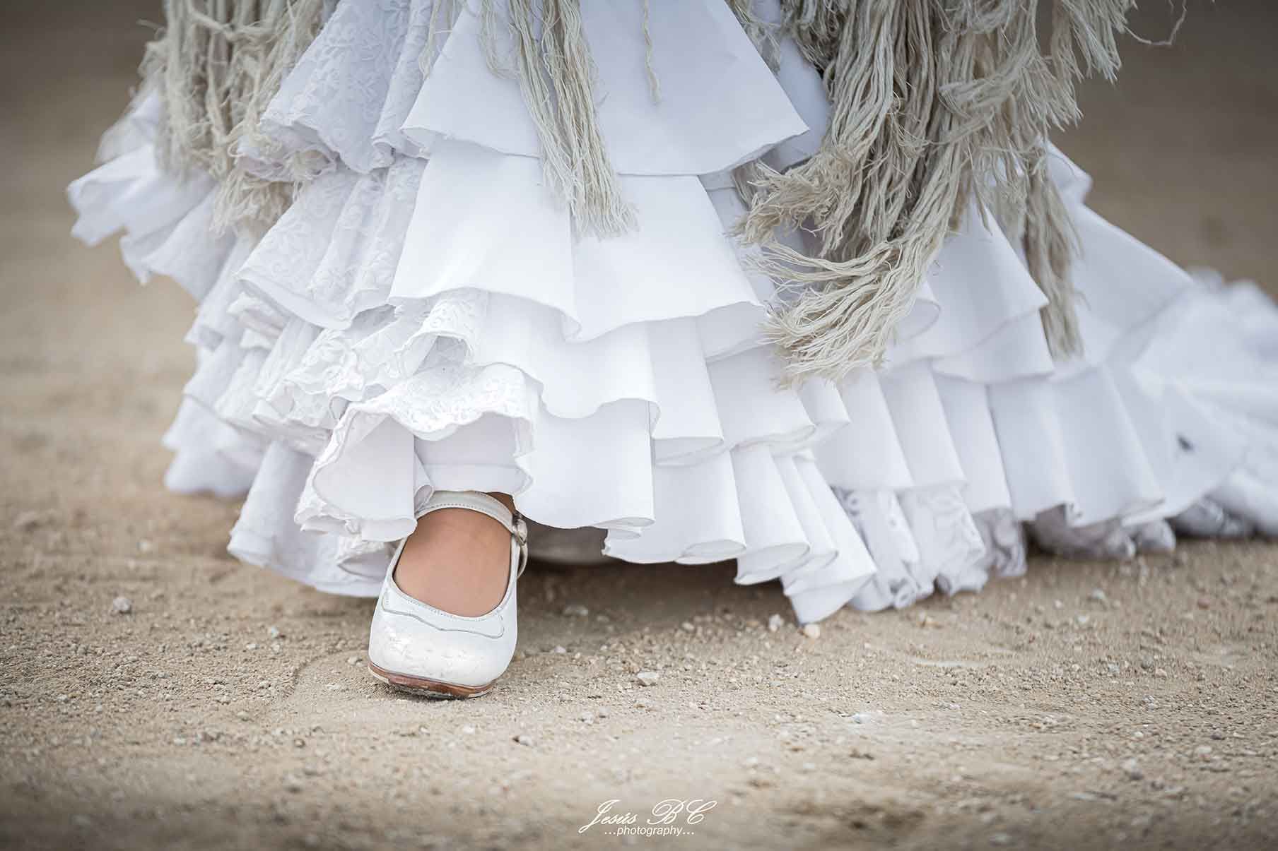 Un primer plano de una persona que lleva un vestido blanco y zapatos blancos.