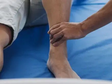 Una persona recibe un masaje en el tobillo sobre una colchoneta azul.
