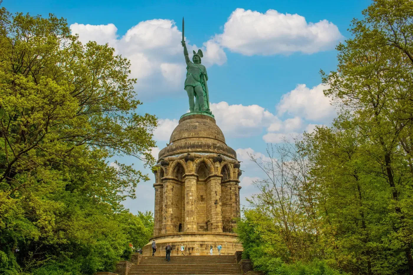 Das Hermannsdenkmal zeigt eine Kupferstatue eines Kriegers, der ein Schwert hochhält, auf einem hohen Steinsockel.