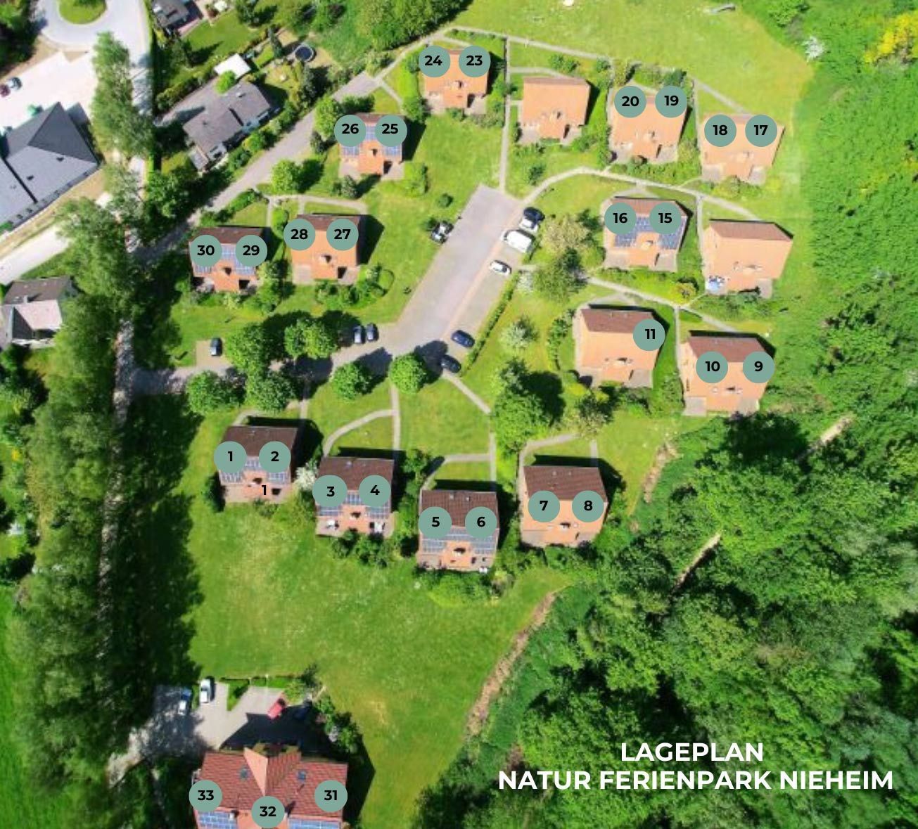 Luftbild des Naturferienparks Nieheim, das nummerierte Ferienhütten zeigt, die um eine zentrale Zufahrt und die Parklandschaft angeordnet sind.