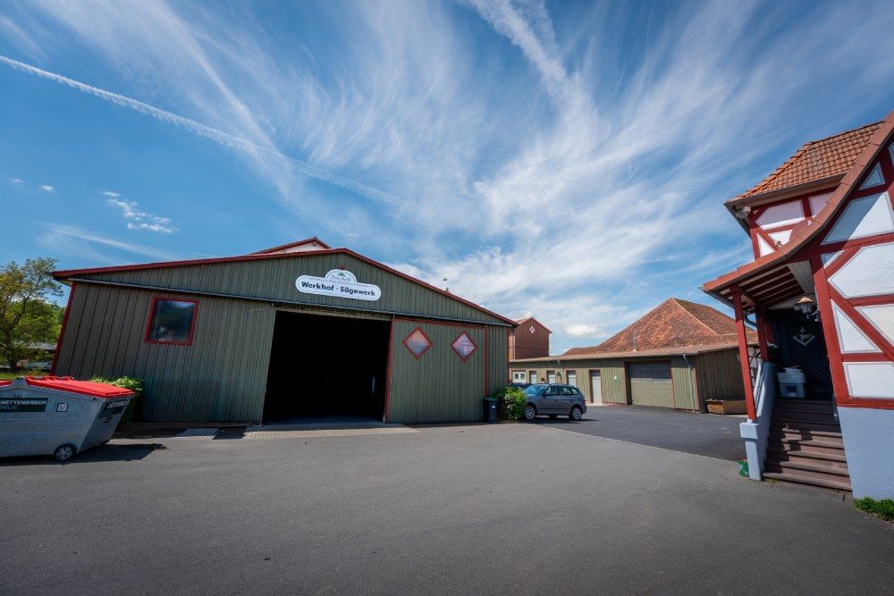 Markthof im Freien mit einer grünen Scheune, Gebäuden mit roten Dächern und einem teilweise bewölkten blauen Himmel