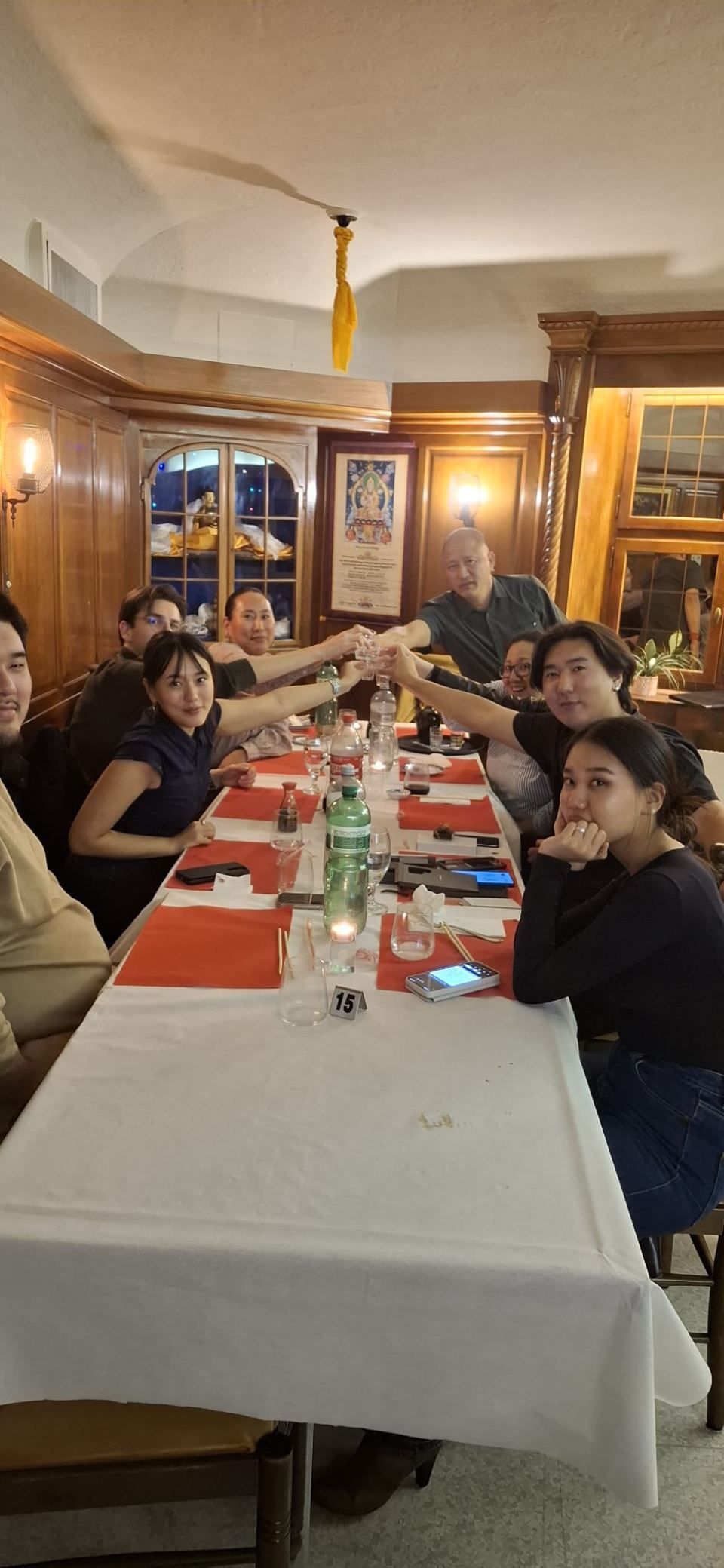 Eine Gruppe stösst an einem Restauranttisch an. Sie sitzen an einem Tisch mit weisser Tischdecke.