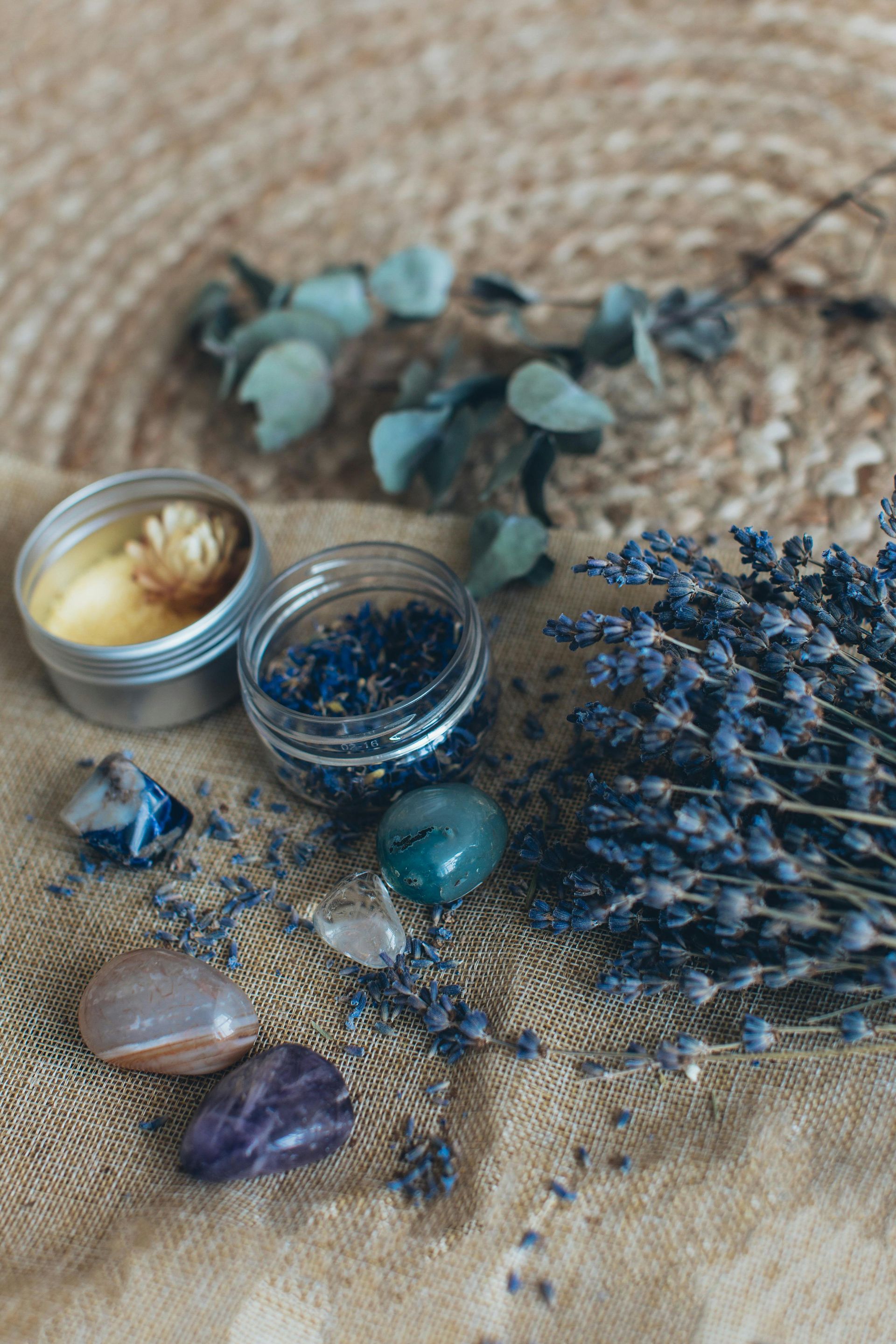 Un ramo de flores violetas, cristales y una vela están sobre una mesa.