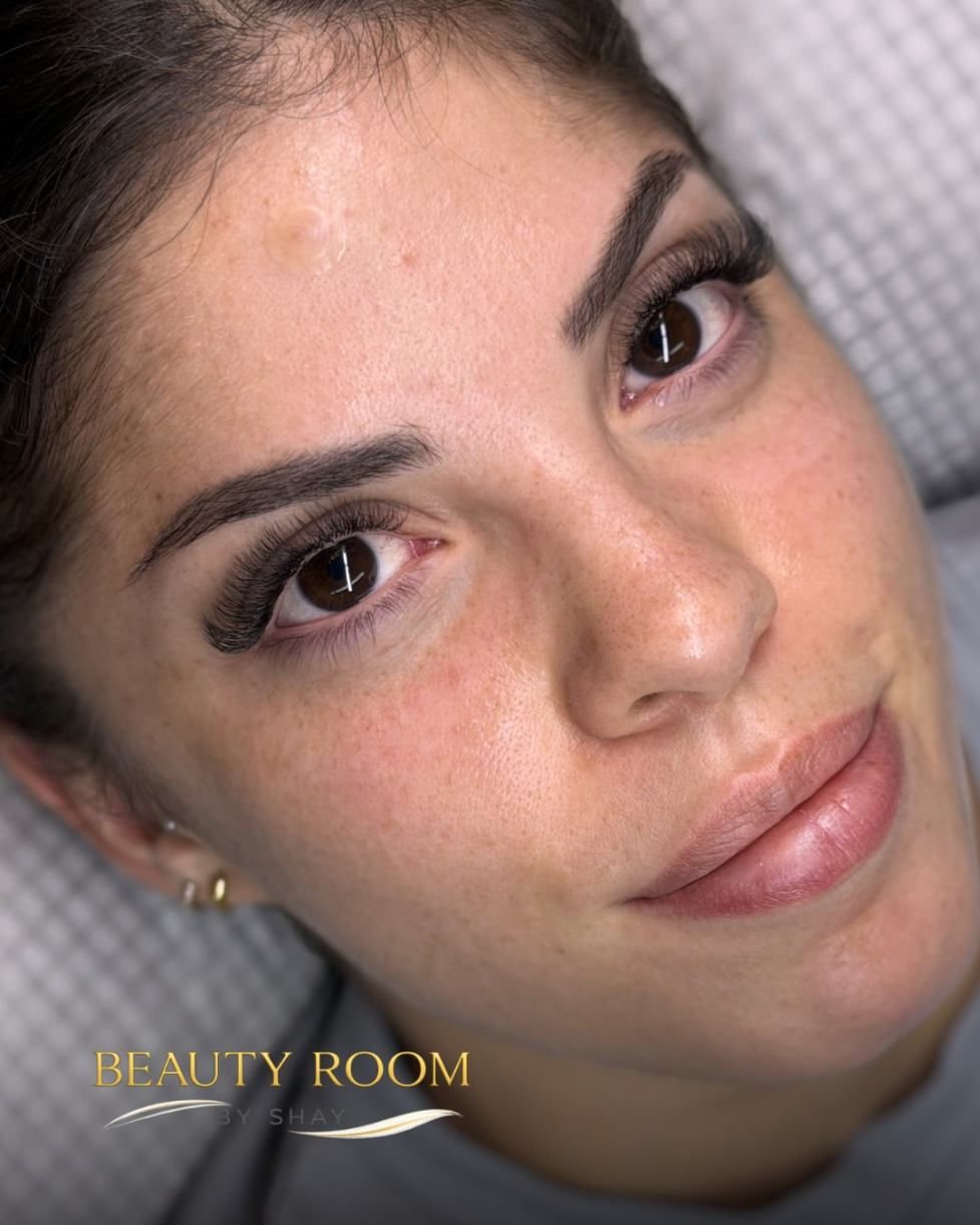 Primer plano de una mujer con maquillaje natural, recostada y mirando a la cámara en un entorno de spa.