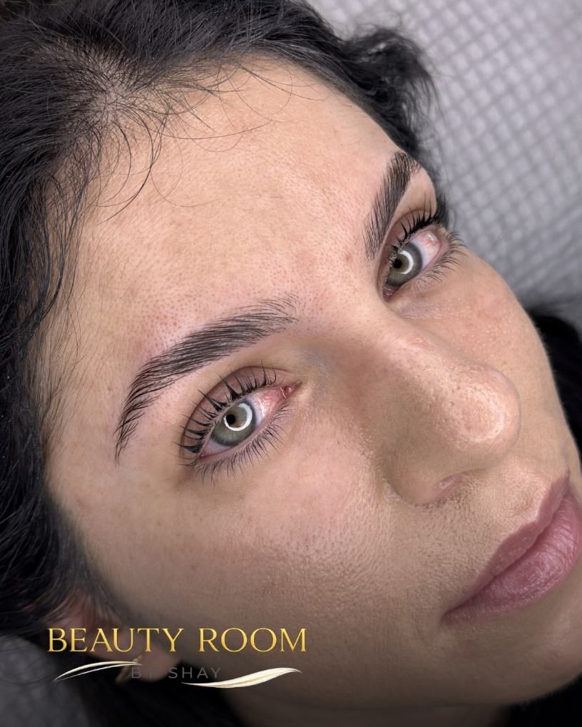 Primer plano de una mujer con cejas arregladas y maquillaje rosa suave en un salón de belleza.