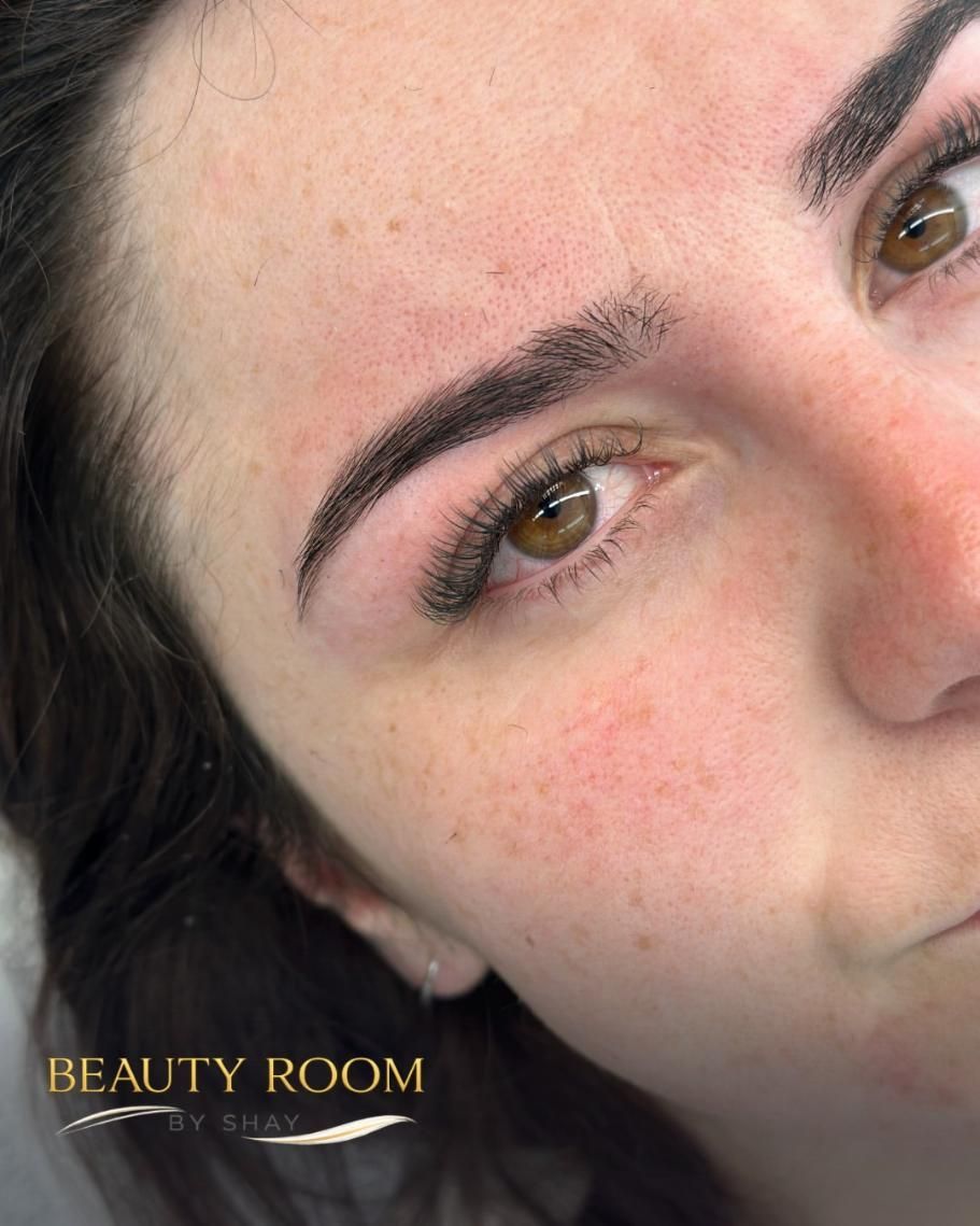 Primer plano del rostro de una mujer con maquillaje natural y cejas arregladas, en una cabina de belleza.