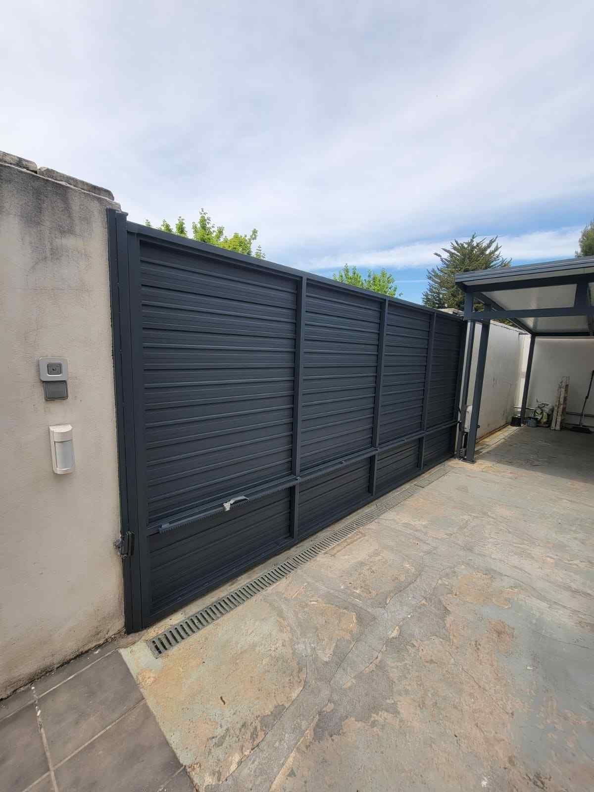 Puerta corredera de color gris oscuro situada a lo largo