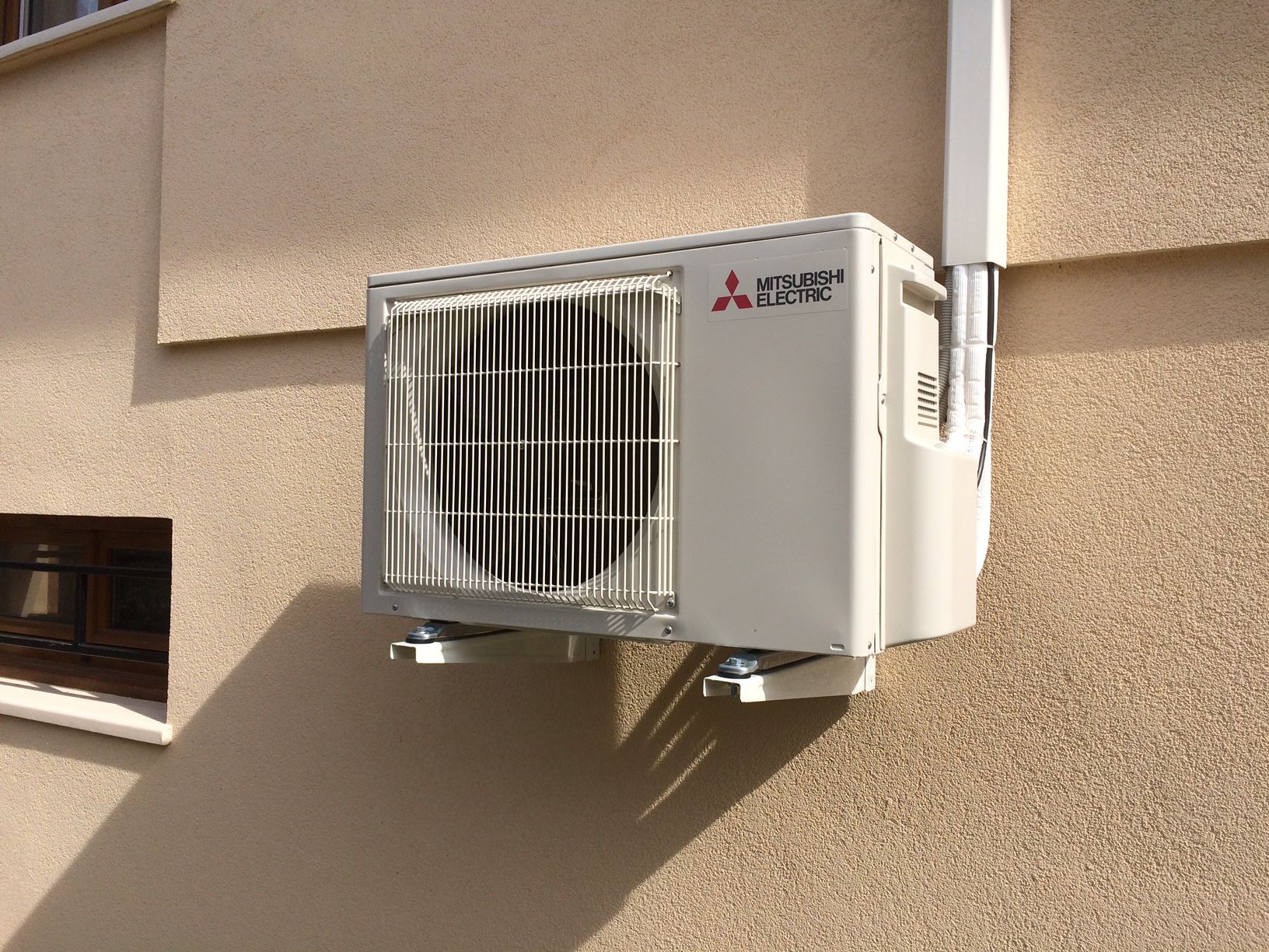 Une pompe à chaleur accrochée à un mur en extérieur