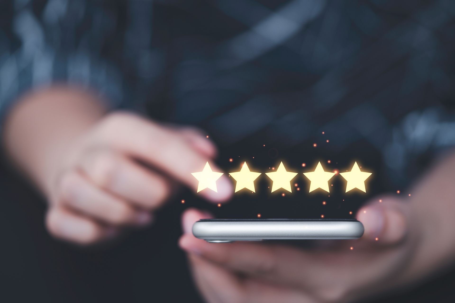 Main tenant un smartphone avec cinq étoiles lumineuses au-dessus de l'écran.