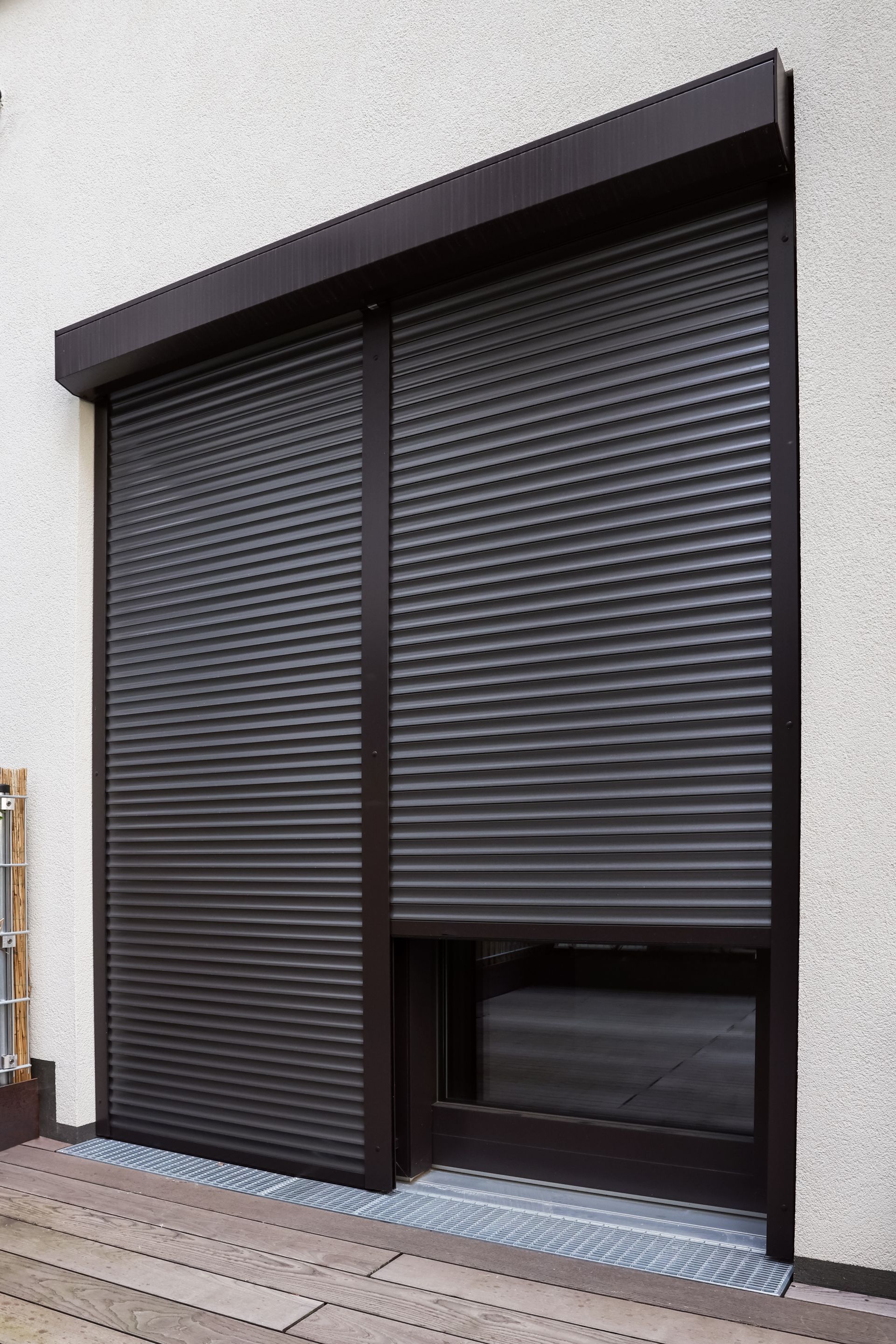 Volet roulant métallique noir sur la façade d'un bâtiment.
