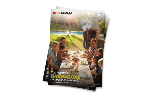 Portada de la revista GAMMA BBQ que muestra a personas cenando al aire libre junto a una parrilla y humo en un jardín soleado.