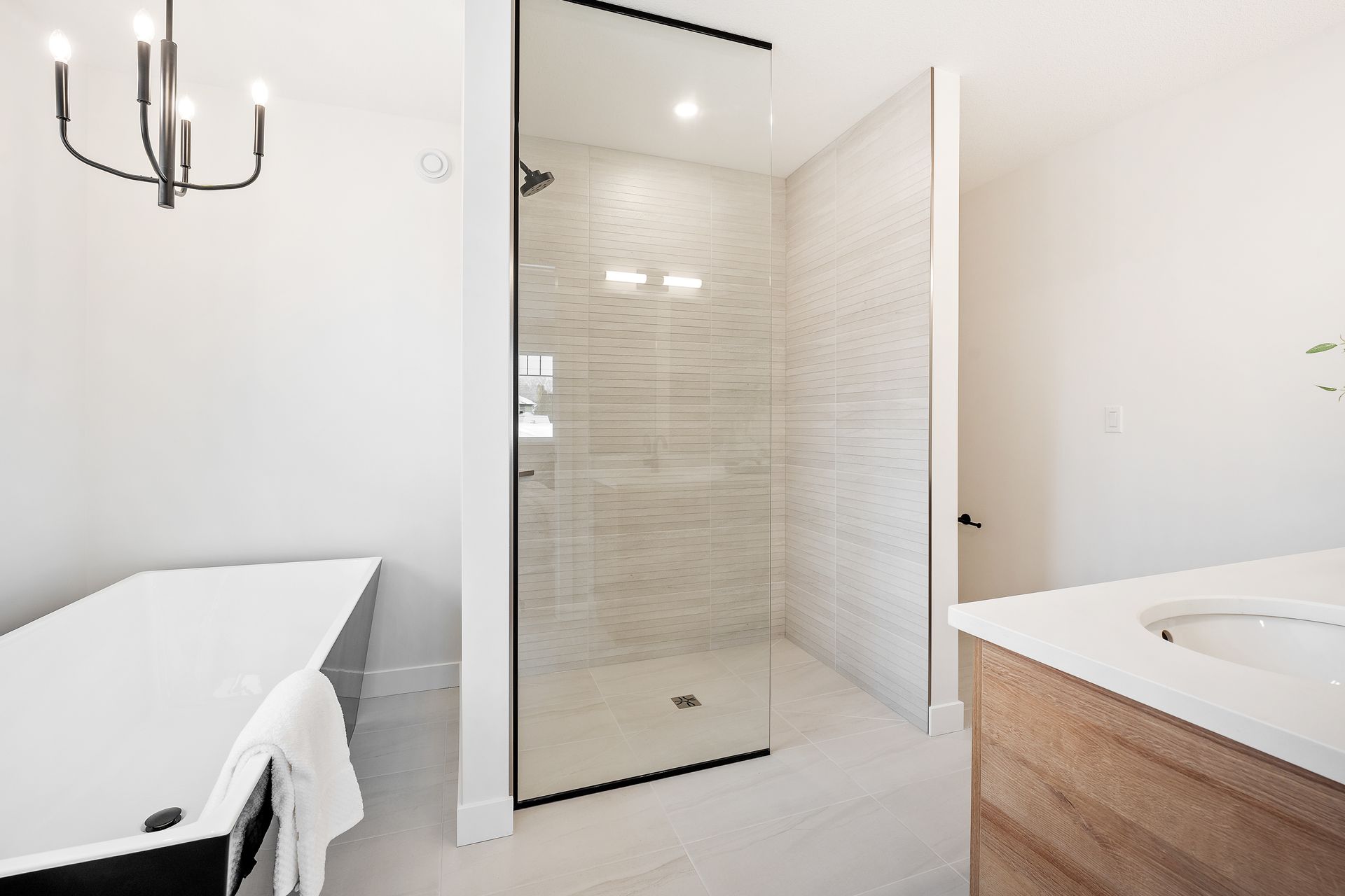 Salle de bains moderne avec douche en verre, carrelage clair, murs blancs et meuble-lavabo en bois.