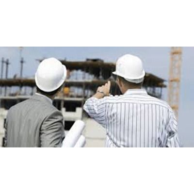 Dos hombres que llevan cascos miran un sitio de construcción.