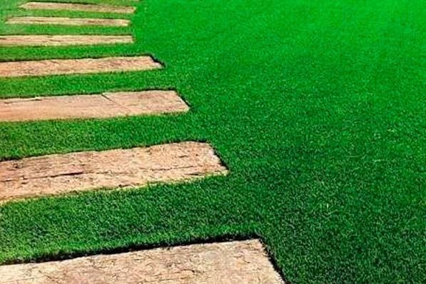 Una hilera de pasarelas de piedra que atraviesan un exuberante campo de césped verde.