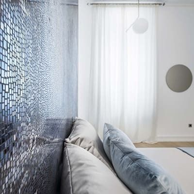 Un dormitorio con una pared azul y cortinas blancas.