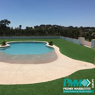 Una gran piscina está rodeada de un exuberante césped verde.