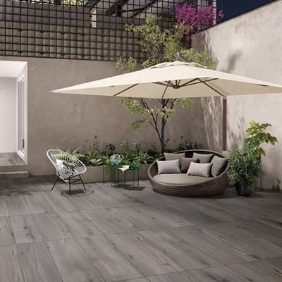Un patio con sofá, silla, mesa y sombrilla.