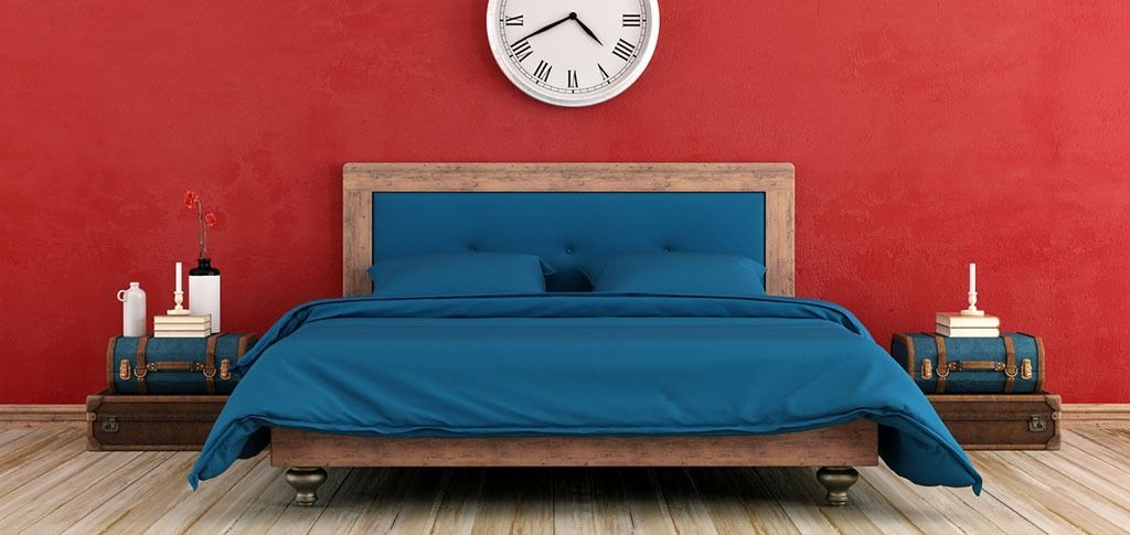 Un dormitorio con una cama, mesitas de noche y un reloj en la pared.