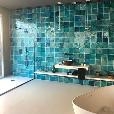 Un baño con azulejos azules en la pared y una bañera.