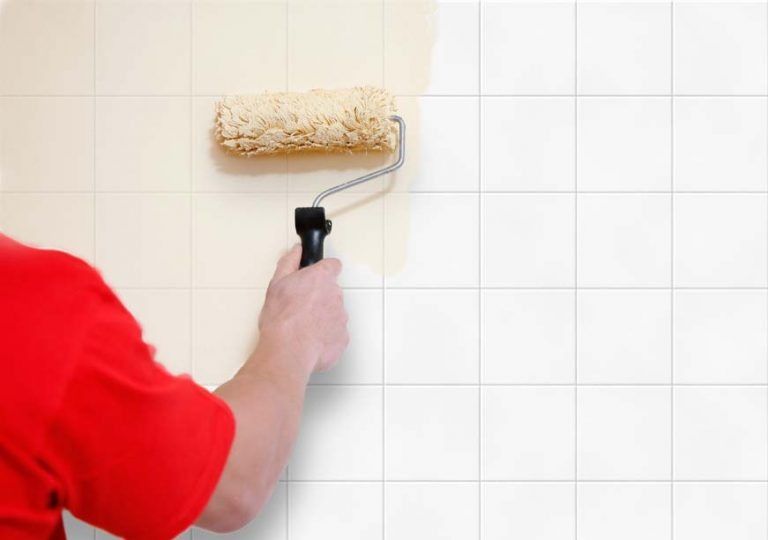 Un hombre con una camisa roja está pintando una pared con un rodillo.