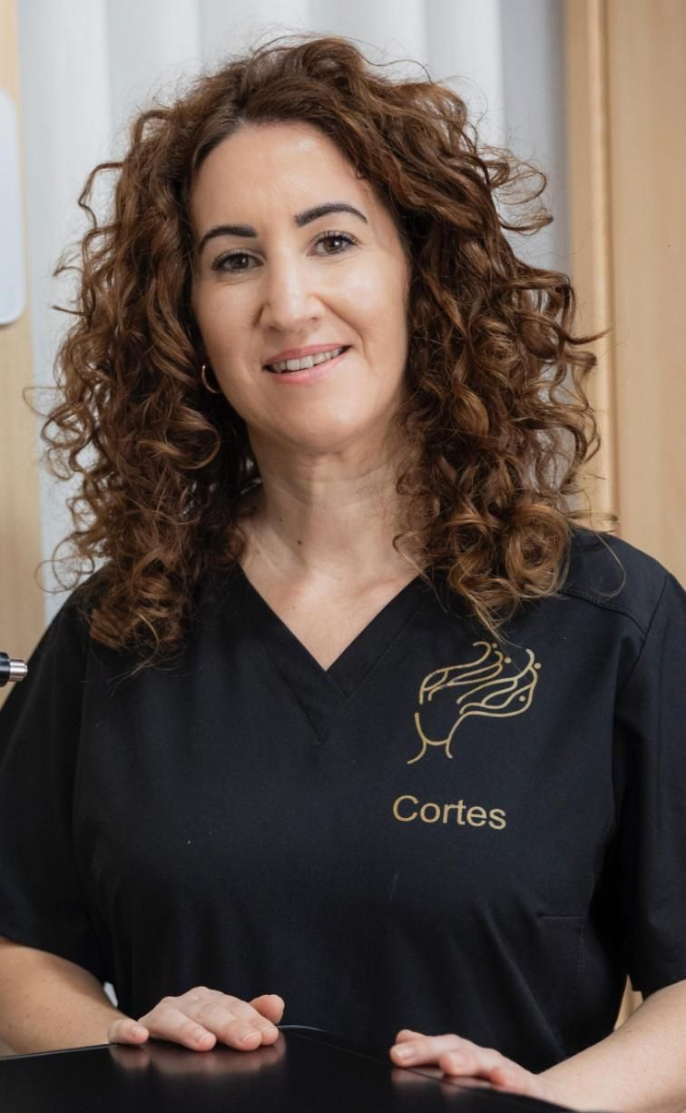 Mujer de cabello rizado con uniforme negro sonriendo. 