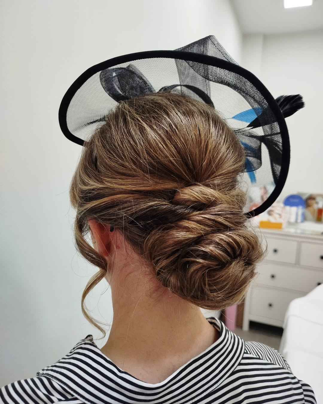 Mujer con peinado recogido, con tocado de red negra y top de rayas.