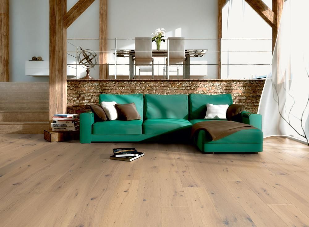 Wohnzimmer mit grünem Sofa, Holzboden, Essbereich und sichtbaren Holzbalken.