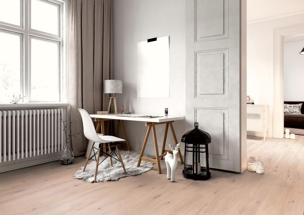 Lichtdurchflutetes Heimbüro mit weißem Schreibtisch, Stuhl und Katze. Holzboden, großes Fenster und offene Tür zu anderen Räumen.