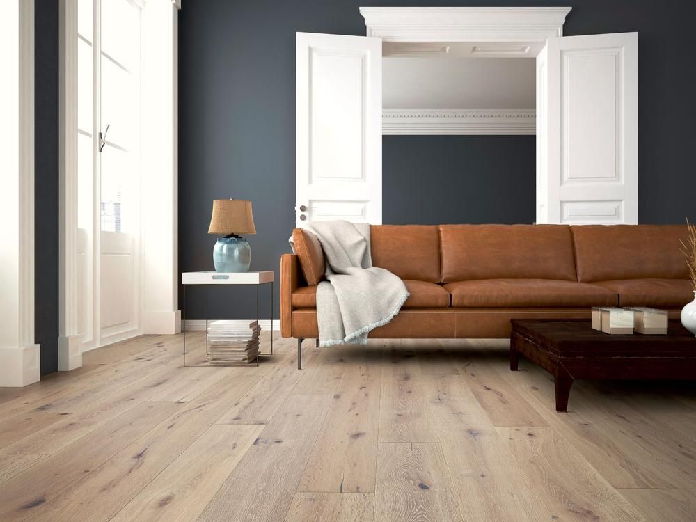 Wohnzimmer mit hellem Holzboden, braunem Ledersofa und dunkelblauer Wand.