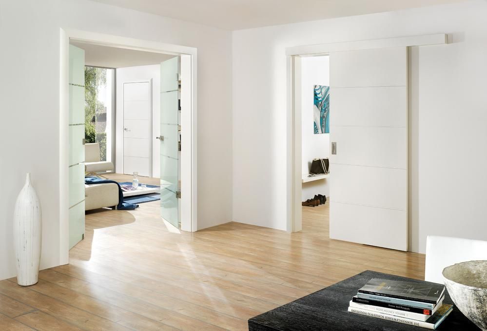Helles, modernes Interieur mit offenen Türen; Holzböden, weiße Wände und dekorative Vasen.