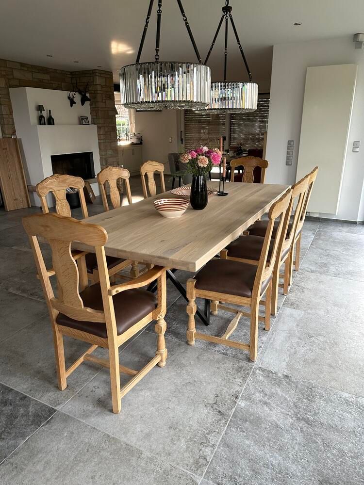 Esszimmer mit großem Holztisch, acht Stühlen mit braunen Sitzen und Kristalllüster.
