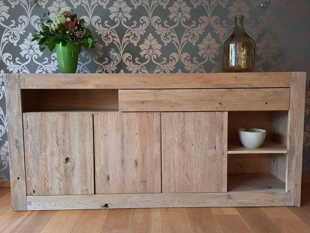 Anrichte aus Holz mit Stauraum, ausgestattet mit Türen, Schublade und Ablage. Auf der Oberseite stehen Blumen und eine Flasche.