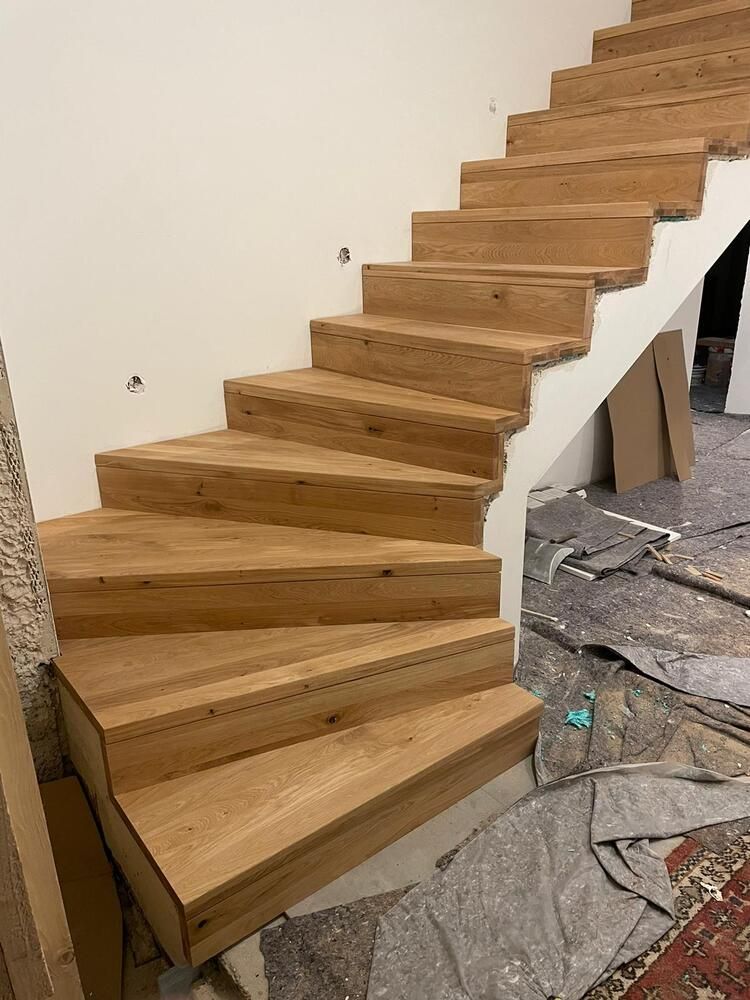Holztreppe mit hellbraunen Stufen und weißer Wand. Baustellenszene.